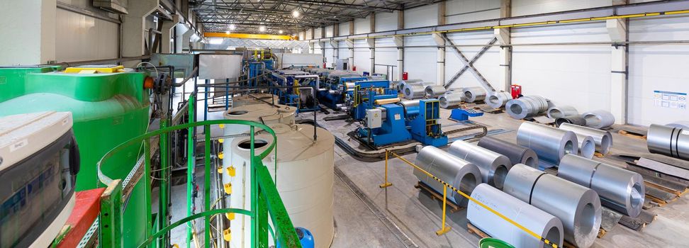 Panoramic photo shot. Steel roofing forming machine. Industrial machine for metal sheet roof coils cut. Process of making steel tile for roof