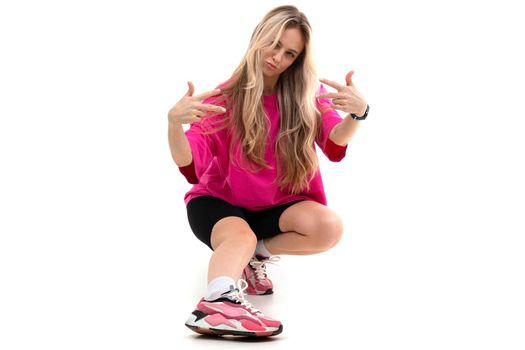 woman on a white background in sportswear sits showing her fingers cool