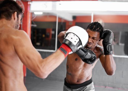 Full-force workout. a two young men practicing kickboxing in a gym.