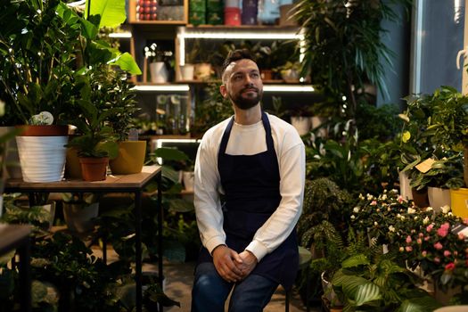 successful businessman florist in flower warehouse among potted plants