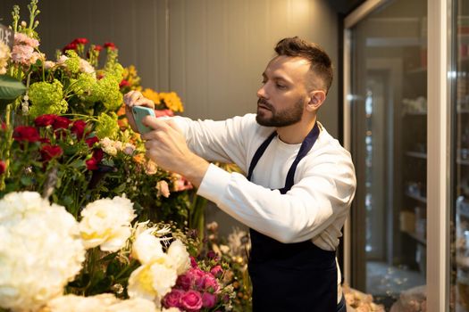 florist chooses flowers for bouquets in the fridge