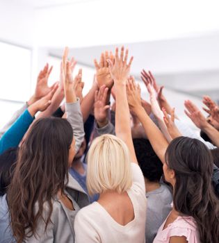 United in business success. a group of businesspeople raising their hands in a huddle.
