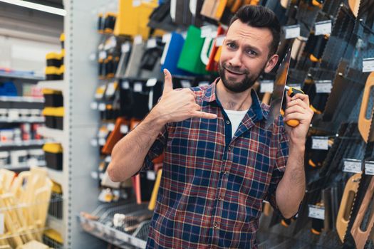 Cheerful shopper in hardware store making fun with wall plastering tool