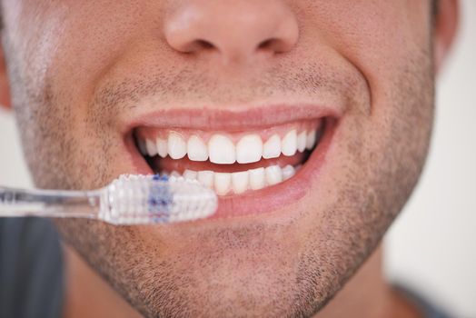 Keeping his teeth sparkly white. a man brushing his teeth.