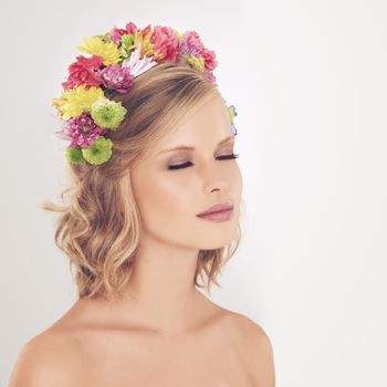 Shes been crowned queen of the spring. A young woman posing with her eyes shut and flowers in her hair.