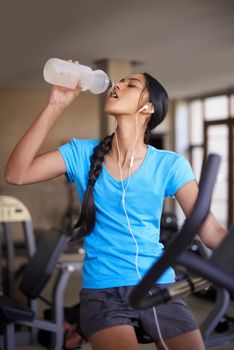 Staying hydrated is important. A teenager on an exercise bike at the gym drinking from a water bottle.