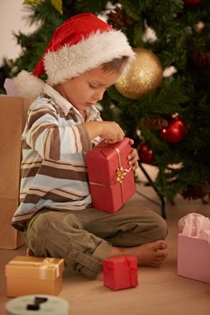 What did Santa bring me. a young boy opening a gift on Christmas.