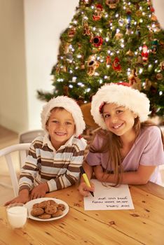 Letters to Santa. Brother and sister writing a letter to Santa and leaving him milk and cookies.