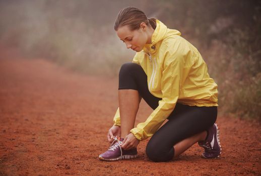 Lacing up before her run. A young female runner tying her shoelaces while out training.