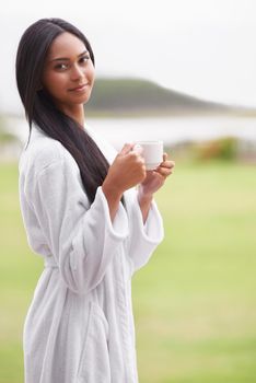 Taking in the tranquility of the moment. A beautiful young woman enjoying a cup of coffee while wearing a bathrobe.