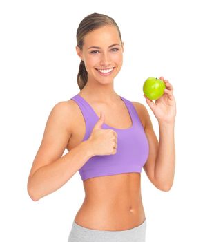 Giving a big thumbs up to healthy eating. Studio portrait of a sporty young woman holding an apple and giving you the thumbs up.