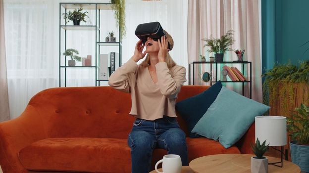 Young woman use virtual reality headset glasses at home, enjoying video concept moving hands in air