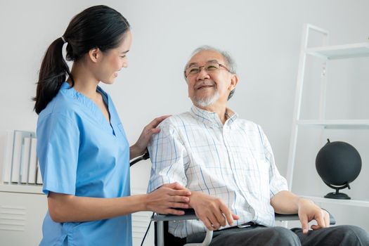 Happy positive asian nurse giving support and touching contented senior man.