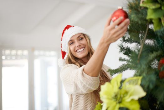 Getting into the Christmas spirit. An attractive woman decorating her christmas tree while at home.