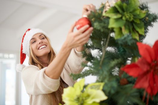 Decorating the tree is always fun. An attractive woman decorating her christmas tree while at home.