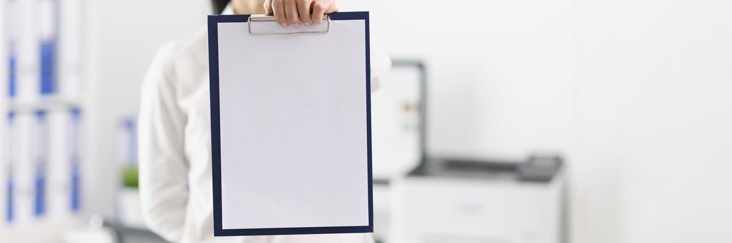Woman in the office shows a folder with a document, mock up