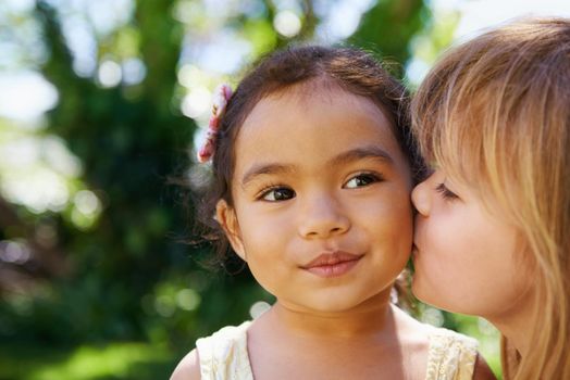 The best of friends. a little girl kissing her friend on the cheek.