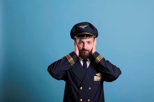 Airliner pilot covering ears with hands