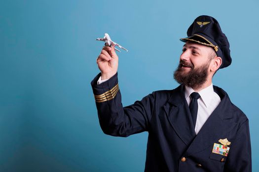 Smiling pilot in uniform holding airplane model