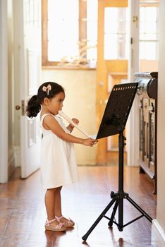 Natural musical talent. A little girl reading musical notation while playing the recorder.