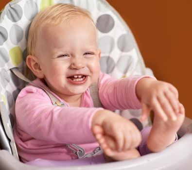 What a happy little one. Cute shot of a happy little baby in a high chair.