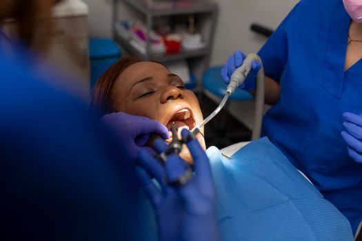 A black woman patient with her mouth open while being treated by her dentist at the dental clinic
