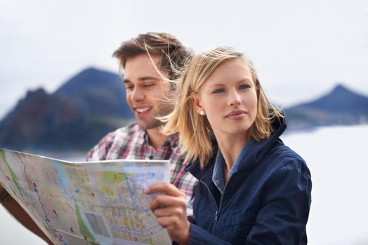 Finding our bearings. A shot of a young couple looking at a map on their road trip.