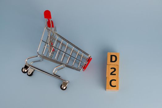 D2c direct to consumer wood cube and shopping cart on background.