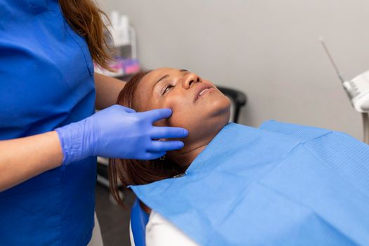A black woman patient laying on the dental chair prior to be treated