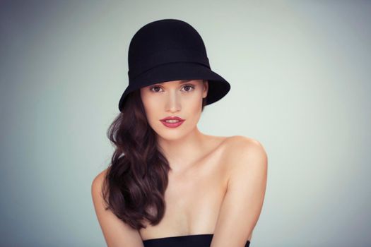 Do you think this hats me. Studio portrait of an attractive and stylish young woman wearing an old-fashioned hat.