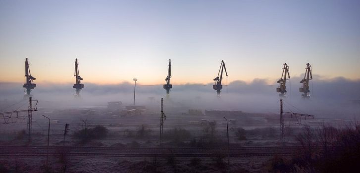 Port cranes shrouded in the morning mist.