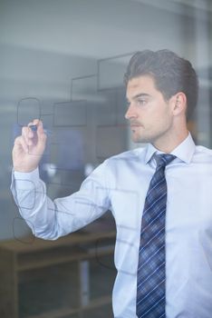 Preparing for his meeting. a businessman drawing on a glass board.