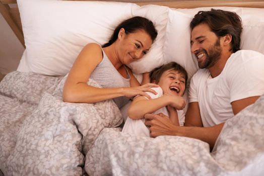 He always wants to be close to mommy and daddy. a young family in bed together.