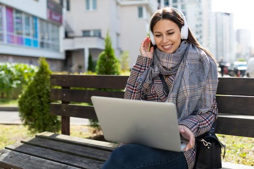 young woman on video chat with laptop and earphone with a smile on her face, the concept of remote work