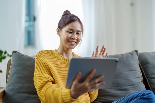 Portrait of a young Asian woman using a tablet on the sofa