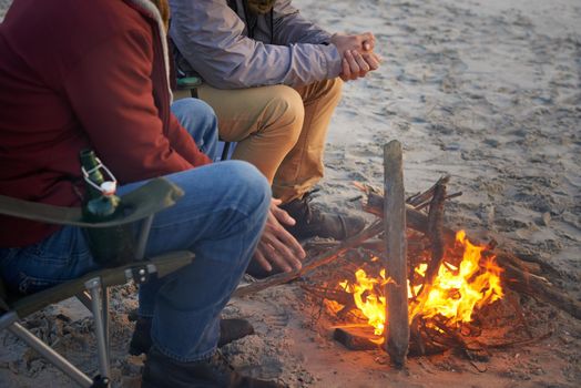 Beach bonding. Two young men sitting around a fire on the beach.