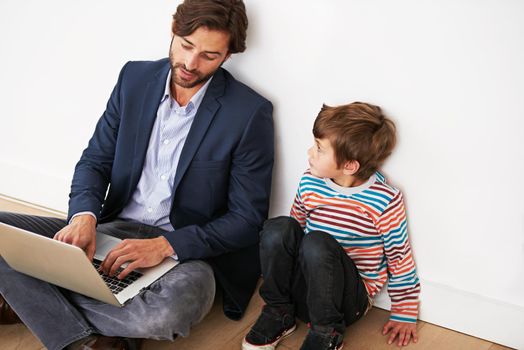 Life is about family and technology. A father and son sitting on the floor with a laptop