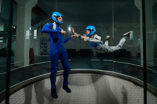 A man teaches a woman how to fly in a wind tunnel. Free fall simulator.