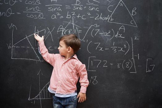 What a little genius. Studio shot of a young boy with a blackboard full of math equations.