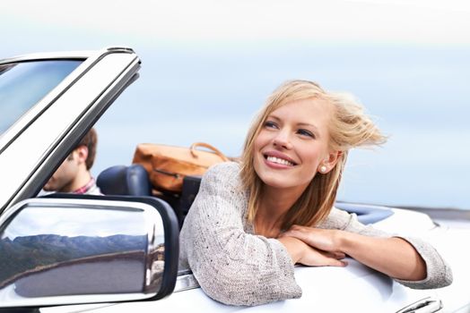 Loving the breeze in her face. a young couple enjoying a drive in a convertible.