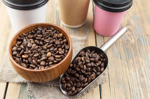 Disposable take-out mockup paper cups with coffee beans for morning espresso and brown bowl on wooden background