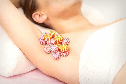 Waxing, depilation armpit concept. Colored round candies lying down on the female armpit, close up.
