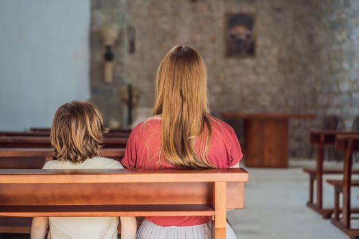 A Christian mom tells her son Bible stories about Jesus sitting in church. Faith, religious education, modern church, mother's day, maternal responsibilities, mother's influence on son's worldview formation