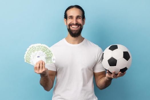 Man showing soccer ball and fun of hundred euro bills, winning lot of money betting for sport.