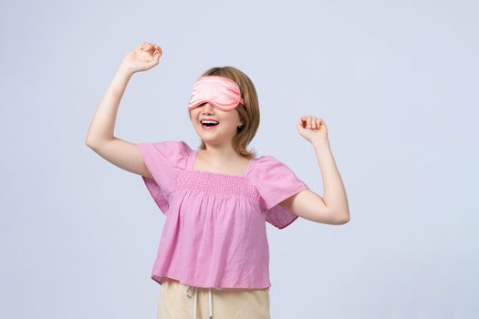 cute young asian woman wearing a pink nightwear, yawning from sleep and tired, on white background
