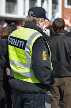 Watchful eye of law enforcement. Rearview shot of a police man during a protest.
