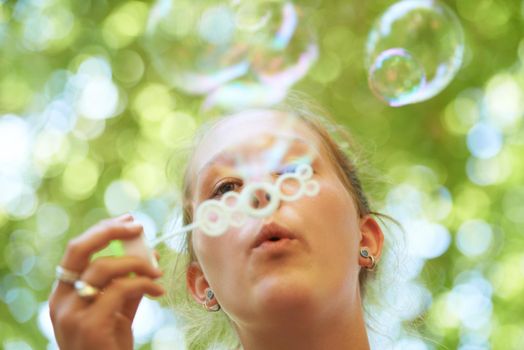 Bubble-blowing blonde. a young woman blowing bubbles outside.