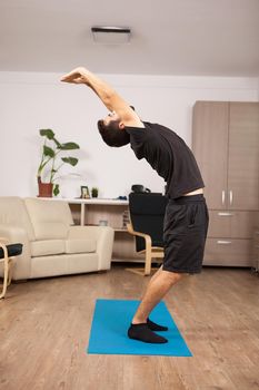 Attractive man with beard doing back stretch standing up
