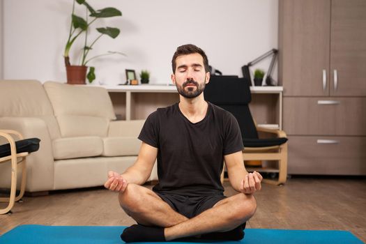 Fit man doing Bound angle yoga pose while he's home.