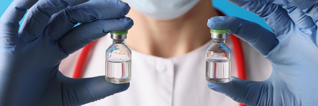 Scientist holding two bottles with injection in blue gloves